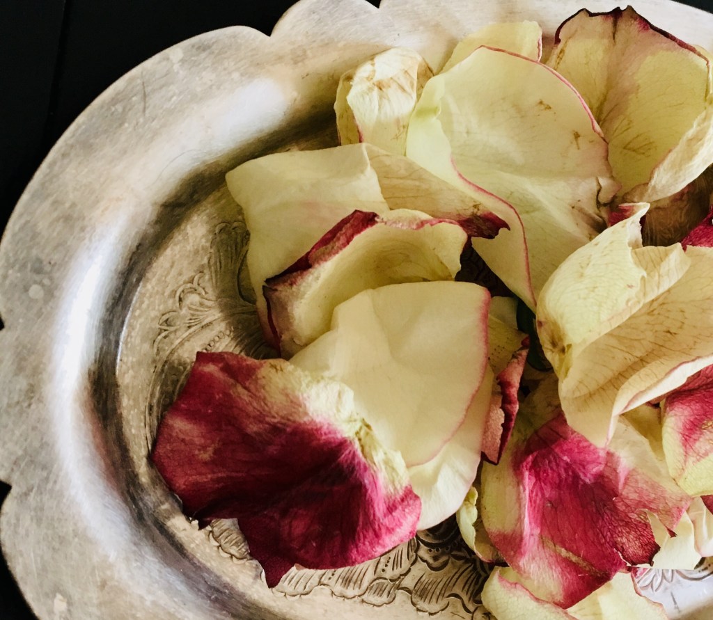 partial view of a small antique silver tray with pink-tipped roses on top